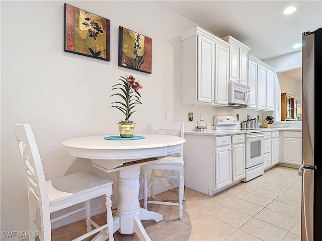 kitchen with white appliances, white cabinets, and light tile patterned floors
