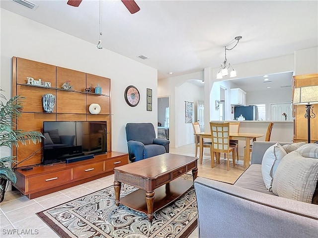 living room featuring visible vents, light tile patterned floors, a ceiling fan, and arched walkways