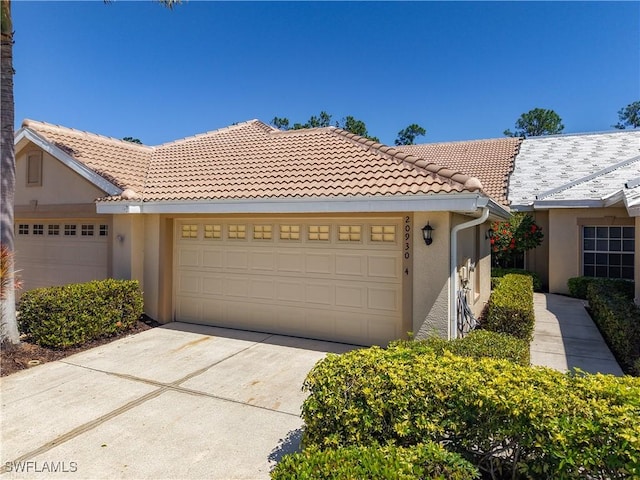 view of front of house with stucco siding, concrete driveway, a tile roof, and a garage