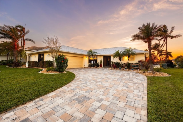 ranch-style house with an attached garage, fence, decorative driveway, and a front yard