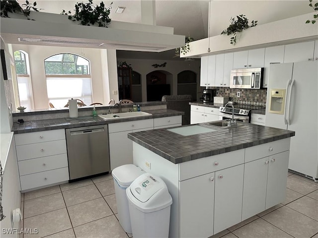 kitchen with stainless steel appliances, a center island, white cabinets, and a sink