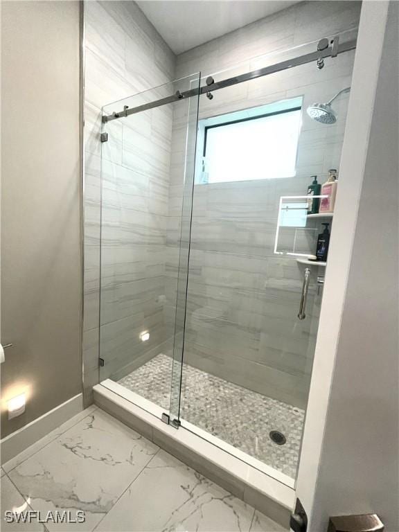 bathroom with marble finish floor, a stall shower, and baseboards