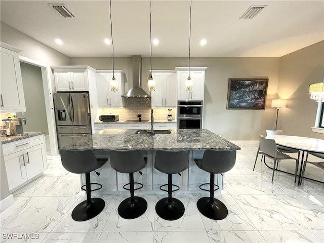 kitchen featuring marble finish floor, visible vents, backsplash, appliances with stainless steel finishes, and wall chimney range hood