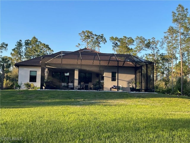 back of house with glass enclosure, a yard, and stucco siding