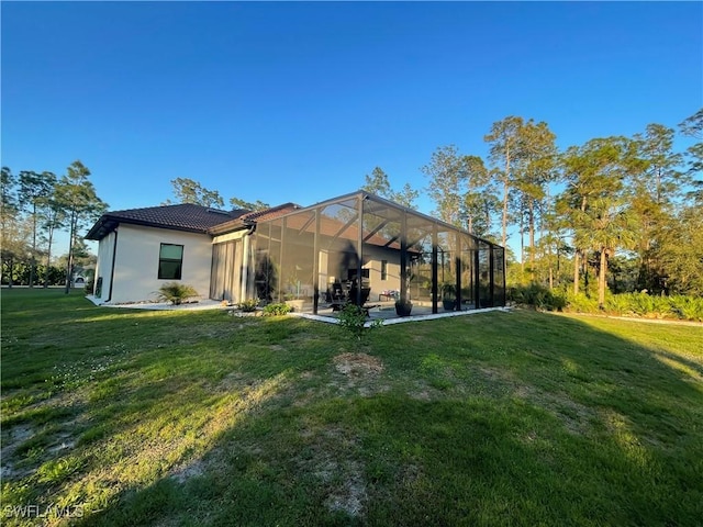 back of house with a lanai, a tiled roof, a patio, and a yard