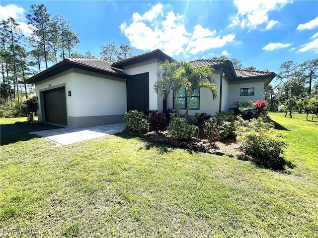 view of front facade featuring a tiled roof, a front yard, and stucco siding