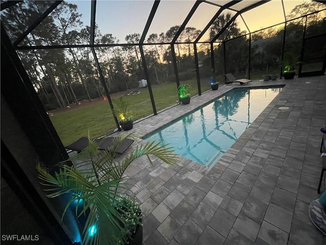 outdoor pool featuring glass enclosure, a patio area, and a lawn