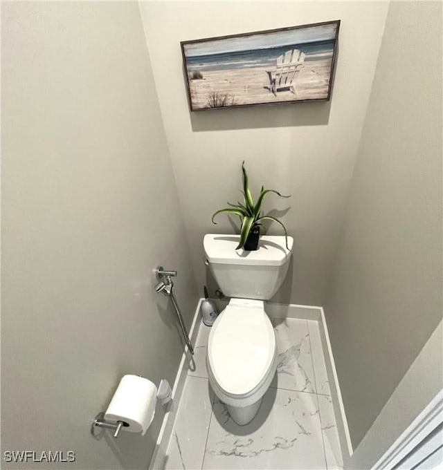 bathroom featuring toilet, marble finish floor, and baseboards