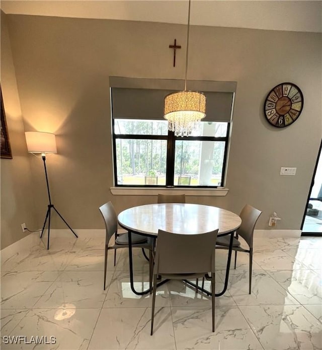 dining space with marble finish floor, baseboards, and a notable chandelier