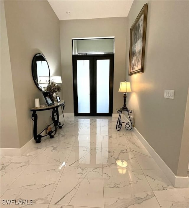 foyer featuring marble finish floor, baseboards, and french doors