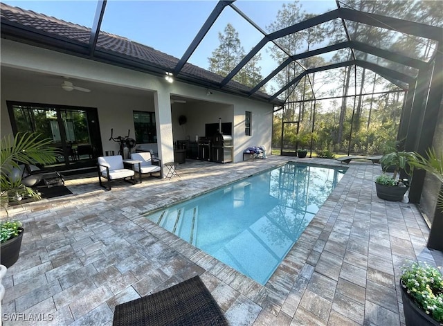 outdoor pool with glass enclosure, a patio area, and a ceiling fan