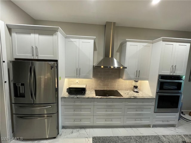 kitchen featuring light stone counters, marble finish floor, appliances with stainless steel finishes, decorative backsplash, and wall chimney exhaust hood