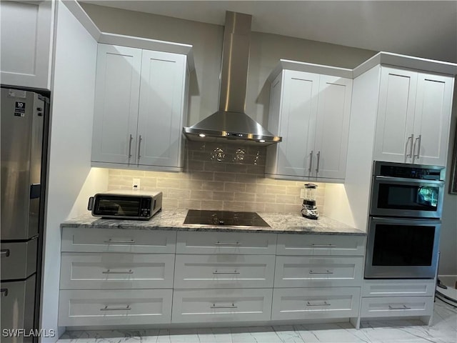 kitchen featuring stainless steel appliances, light stone counters, wall chimney exhaust hood, and tasteful backsplash