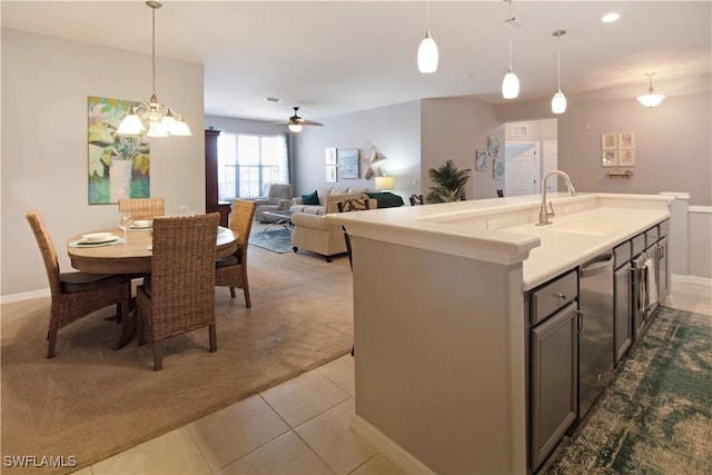 kitchen featuring decorative light fixtures, light tile patterned floors, a kitchen island with sink, light carpet, and a sink