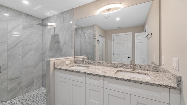 full bathroom featuring double vanity, visible vents, a sink, and tiled shower