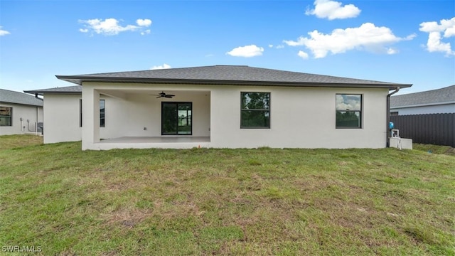 rear view of property with ceiling fan, fence, a lawn, stucco siding, and a patio area