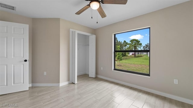 unfurnished bedroom with light wood finished floors, a closet, visible vents, a ceiling fan, and baseboards