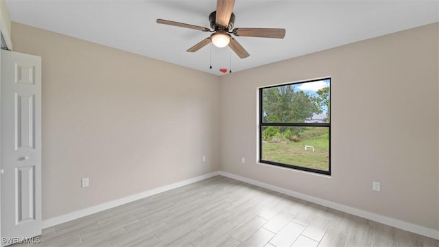 unfurnished room with light wood-type flooring, a ceiling fan, and baseboards