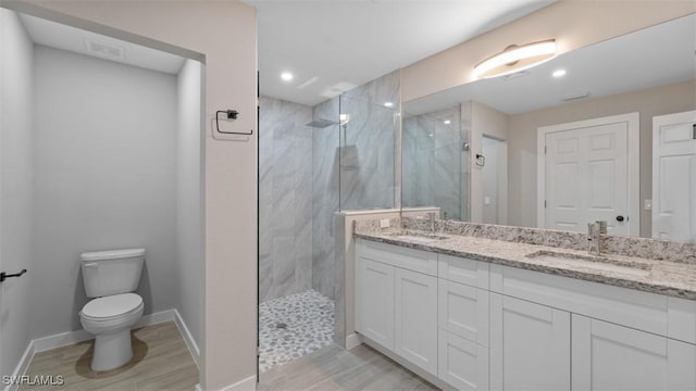 full bathroom with toilet, a sink, a marble finish shower, and double vanity