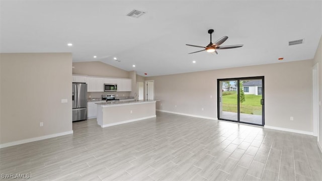 unfurnished living room with vaulted ceiling, light wood finished floors, visible vents, and baseboards