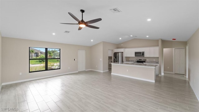 unfurnished living room with visible vents, vaulted ceiling, ceiling fan, light wood-type flooring, and baseboards