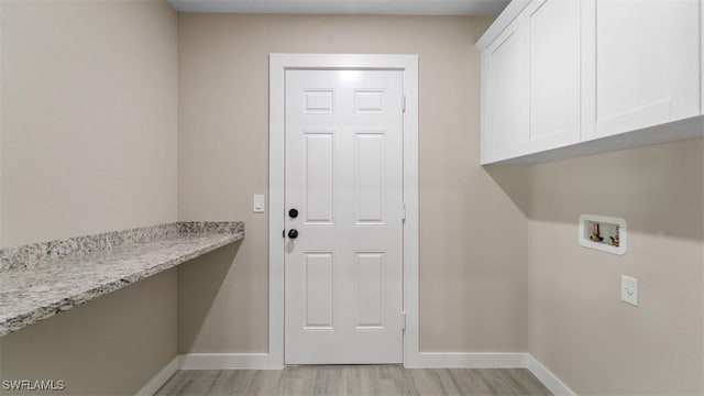 washroom with light wood-type flooring, hookup for a washing machine, cabinet space, and baseboards