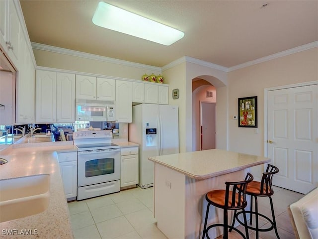 kitchen featuring a breakfast bar, arched walkways, ornamental molding, white cabinets, and white appliances