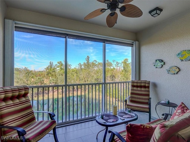 sunroom / solarium with ceiling fan and a wooded view