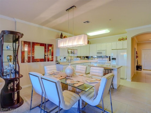 dining area with arched walkways, crown molding, light tile patterned floors, visible vents, and baseboards