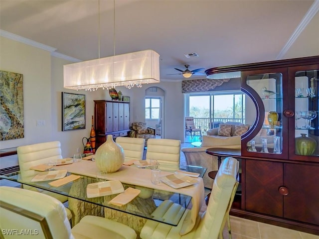 tiled dining room featuring a ceiling fan, visible vents, and crown molding