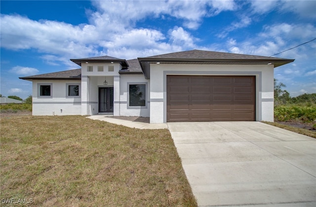 prairie-style home with a garage, driveway, a shingled roof, stucco siding, and a front yard