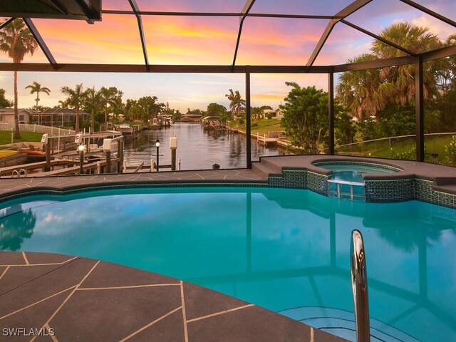 pool at dusk featuring boat lift, a lanai, a pool with connected hot tub, a dock, and a patio area