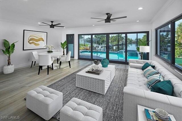 living area featuring ornamental molding, plenty of natural light, wood finished floors, and recessed lighting