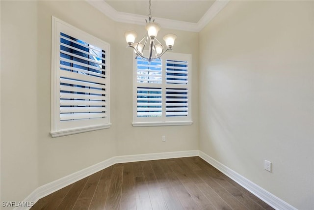 unfurnished dining area featuring dark wood-style floors, crown molding, a notable chandelier, and baseboards