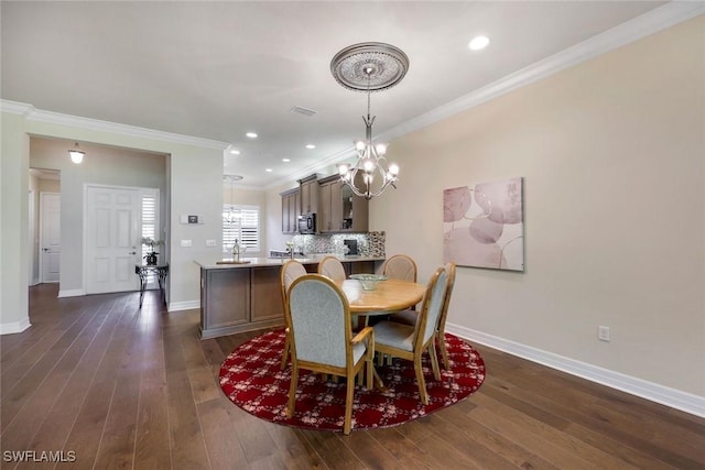 dining space with ornamental molding, dark wood-style flooring, a chandelier, and baseboards