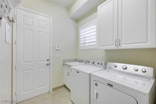 laundry area featuring light tile patterned floors, a sink, baseboards, washer and dryer, and cabinet space