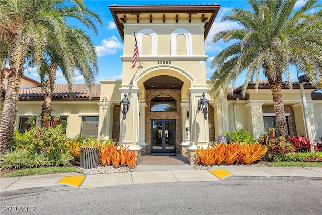 property entrance with french doors, a tile roof, and stucco siding