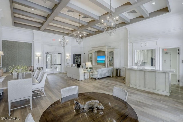 dining room featuring light wood-style floors, french doors, a notable chandelier, and a high ceiling