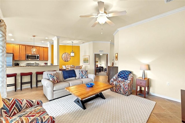 living area with light tile patterned floors, baseboards, a ceiling fan, and ornate columns