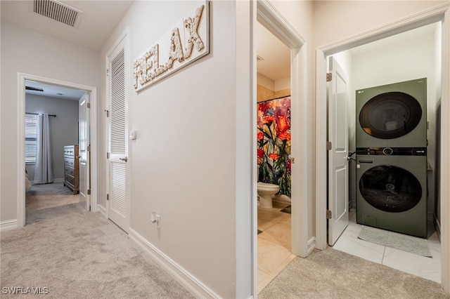 washroom with carpet floors, stacked washer and dryer, visible vents, laundry area, and baseboards