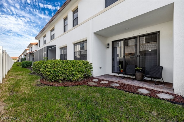 exterior space featuring a patio area, a lawn, and stucco siding