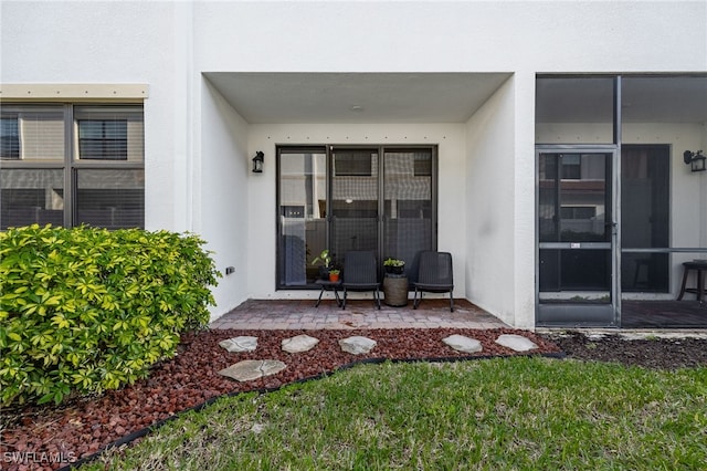 entrance to property with a patio and stucco siding