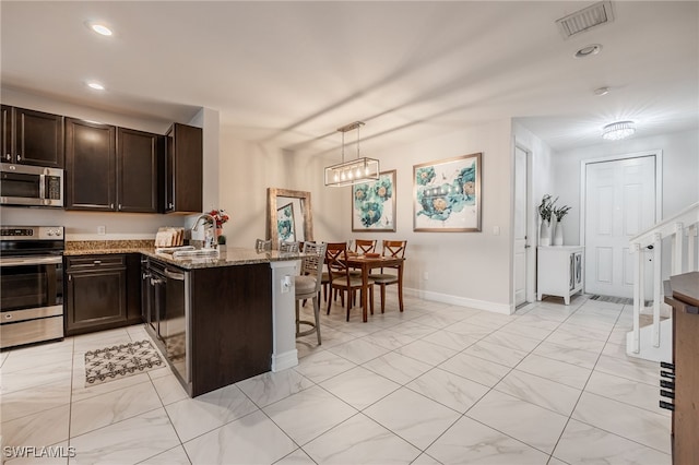 kitchen featuring visible vents, light stone counters, stainless steel appliances, dark brown cabinets, and a sink