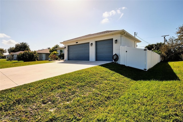 exterior space with an attached garage, fence, driveway, stucco siding, and a front lawn