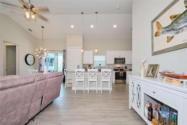 living area featuring light wood-style floors, recessed lighting, high vaulted ceiling, and ceiling fan with notable chandelier