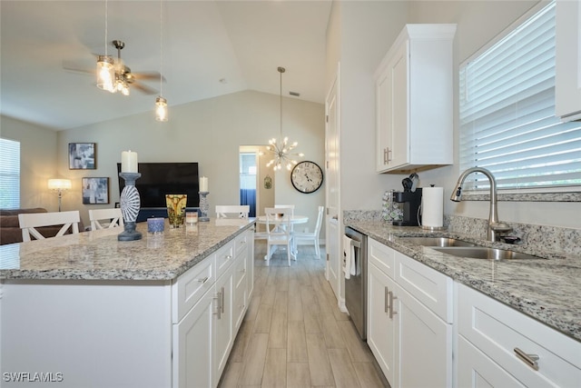 kitchen featuring a kitchen island, a sink, vaulted ceiling, open floor plan, and dishwasher