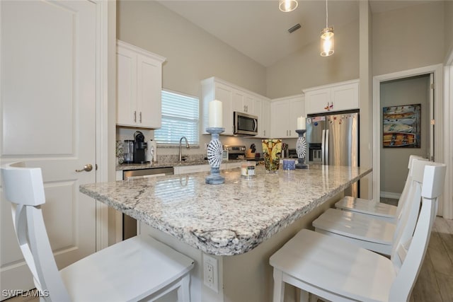 kitchen with white cabinetry, visible vents, appliances with stainless steel finishes, and a breakfast bar area