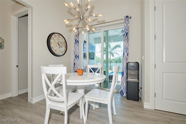 dining space featuring light wood-type flooring, a notable chandelier, and baseboards