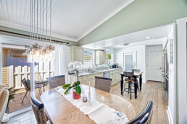 dining room featuring vaulted ceiling, light wood-style floors, a chandelier, and crown molding