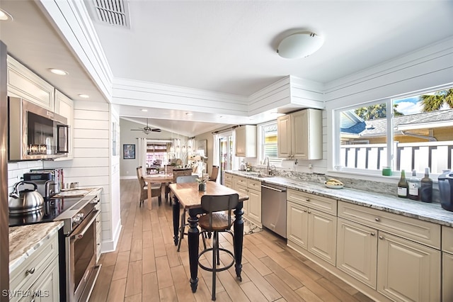 kitchen with light wood finished floors, light stone counters, appliances with stainless steel finishes, and visible vents